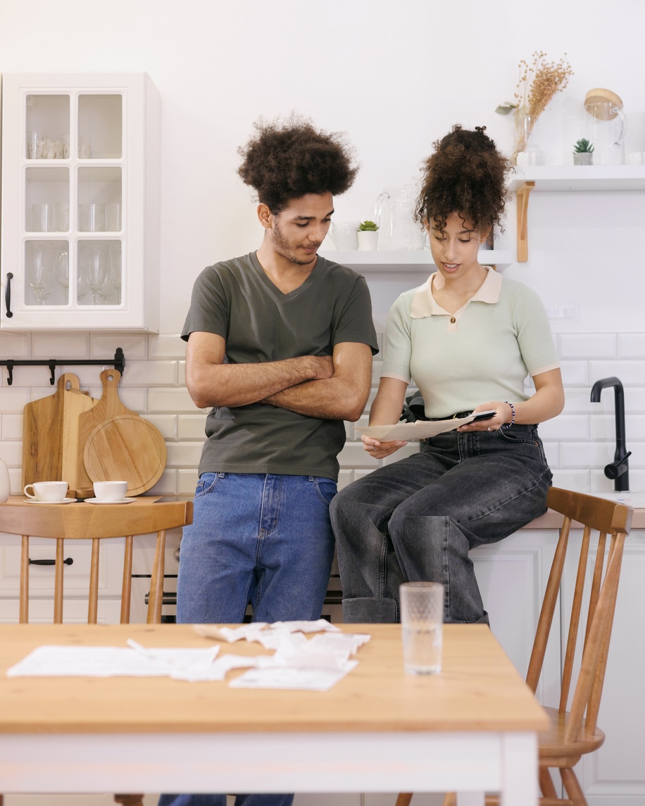 couple man woman are sitting on table in kitchen paying electricity and rent bills. African American young married person in kitchen count expenses on calculator. financial obligations mortgage loan couple man woman are sitting on table in kitchen paying electricity and rent bills.